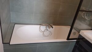 Rénovation d'une salle de bains complète avec joint noir autour de la baignoire